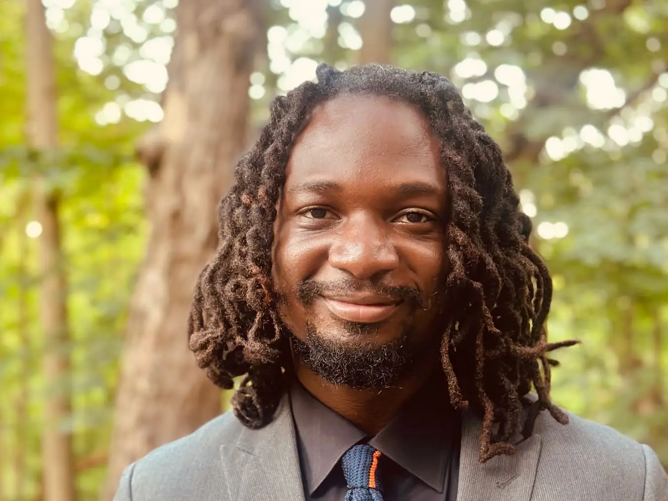 head shot of a man in a suit in front of trees
