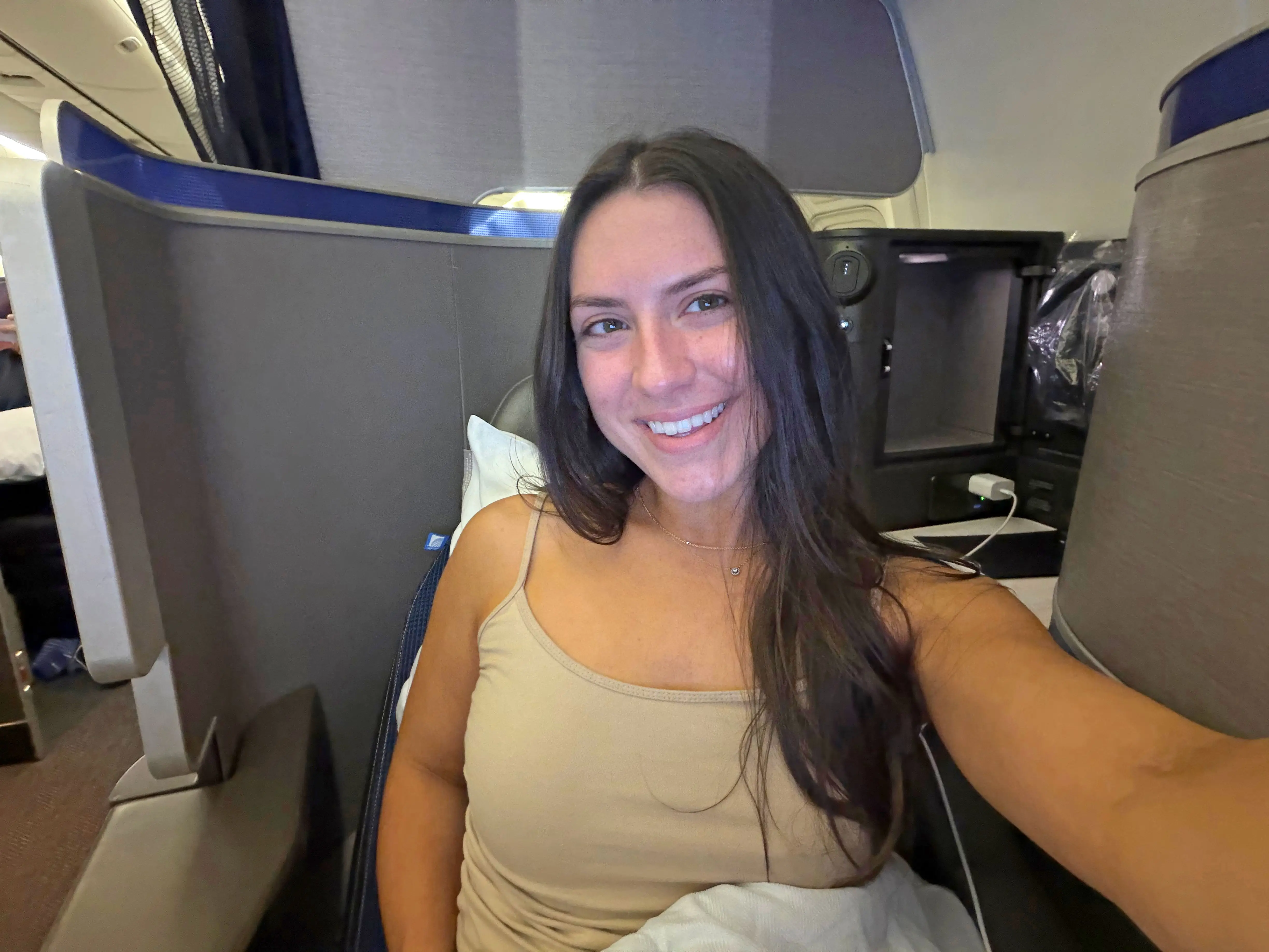 Amanda taking a selfie while sitting in a business-class seat.