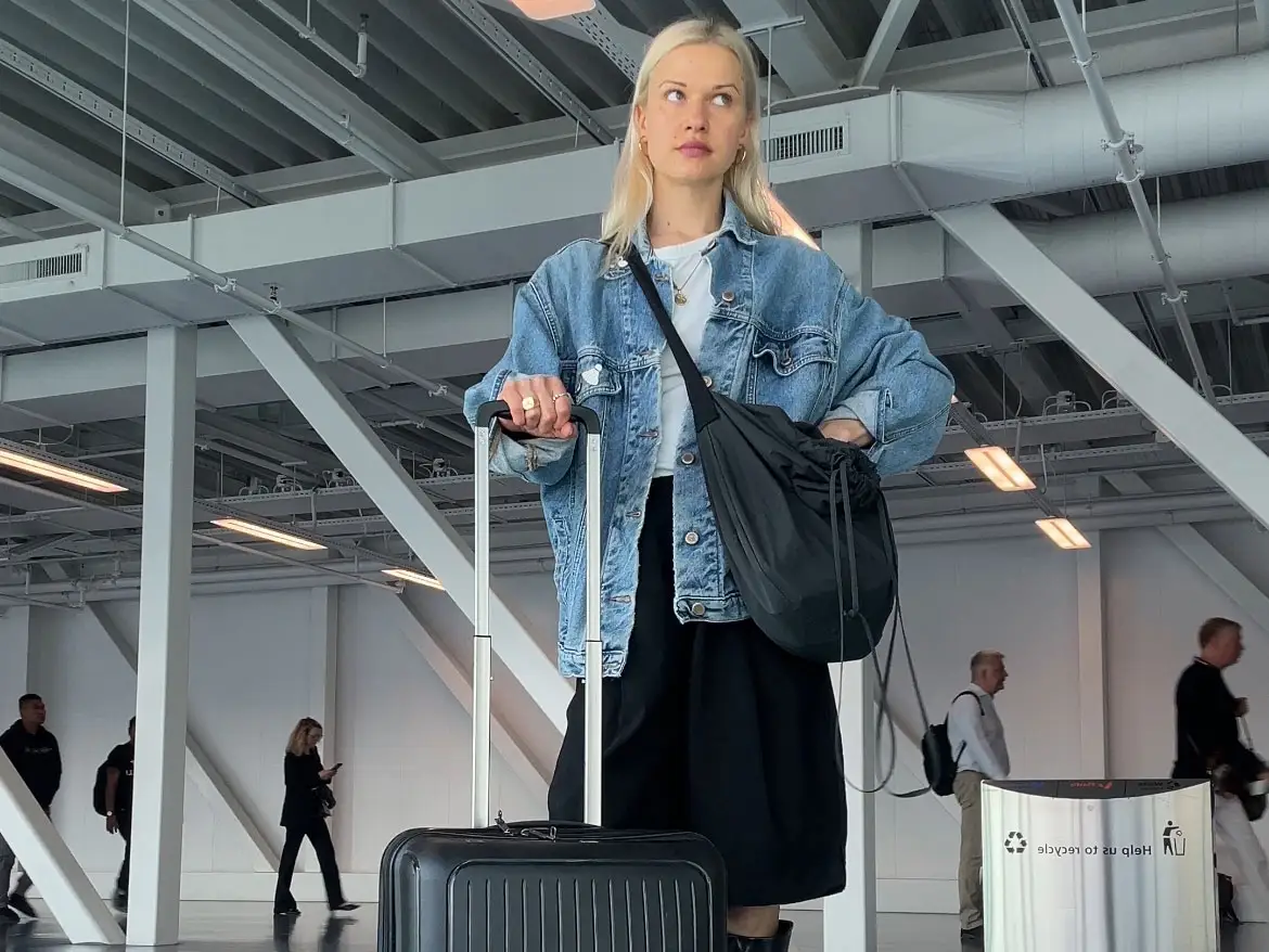 Ilze stands in an airport with luggage.
