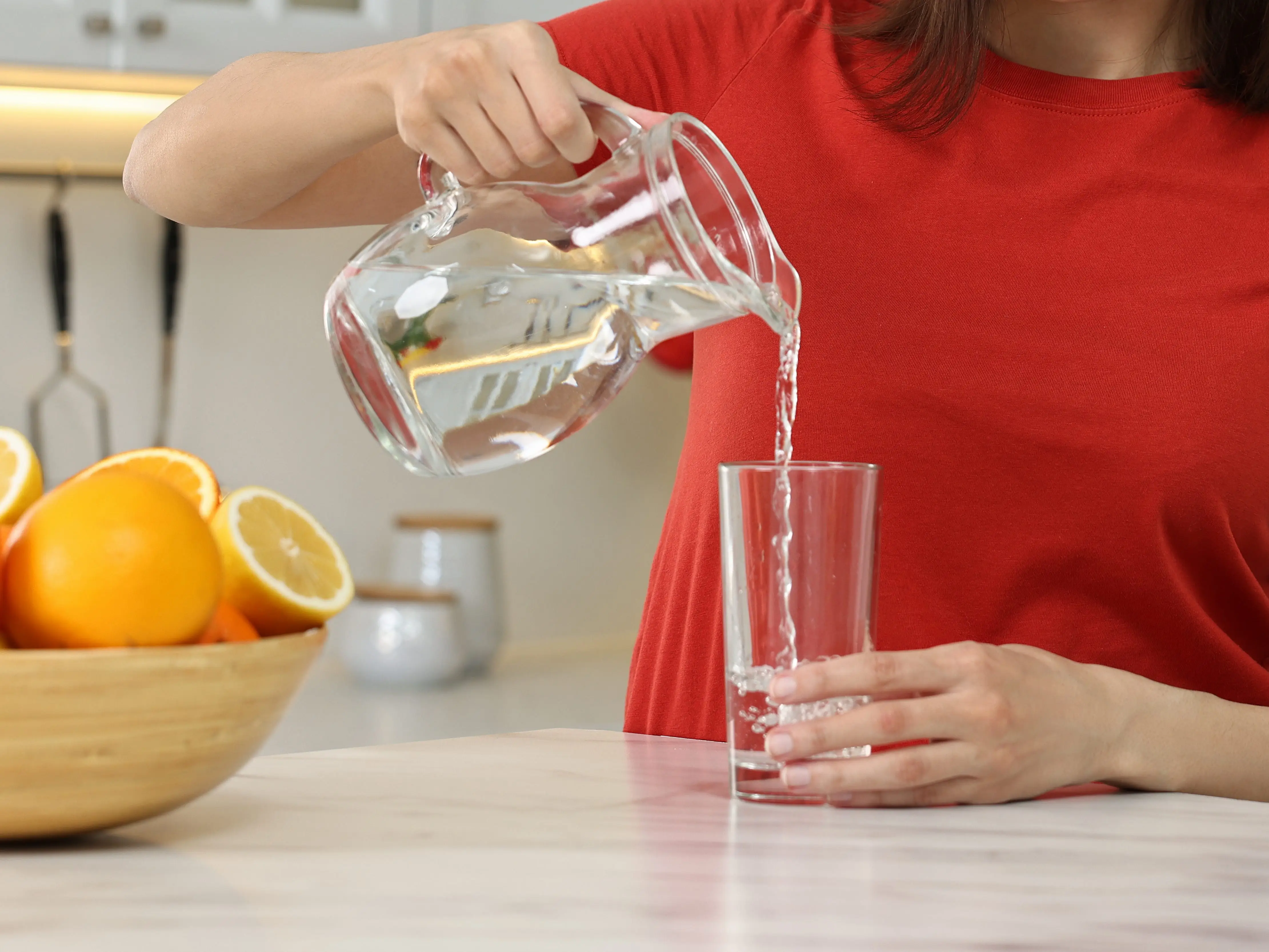 A woman pours water into a glass.