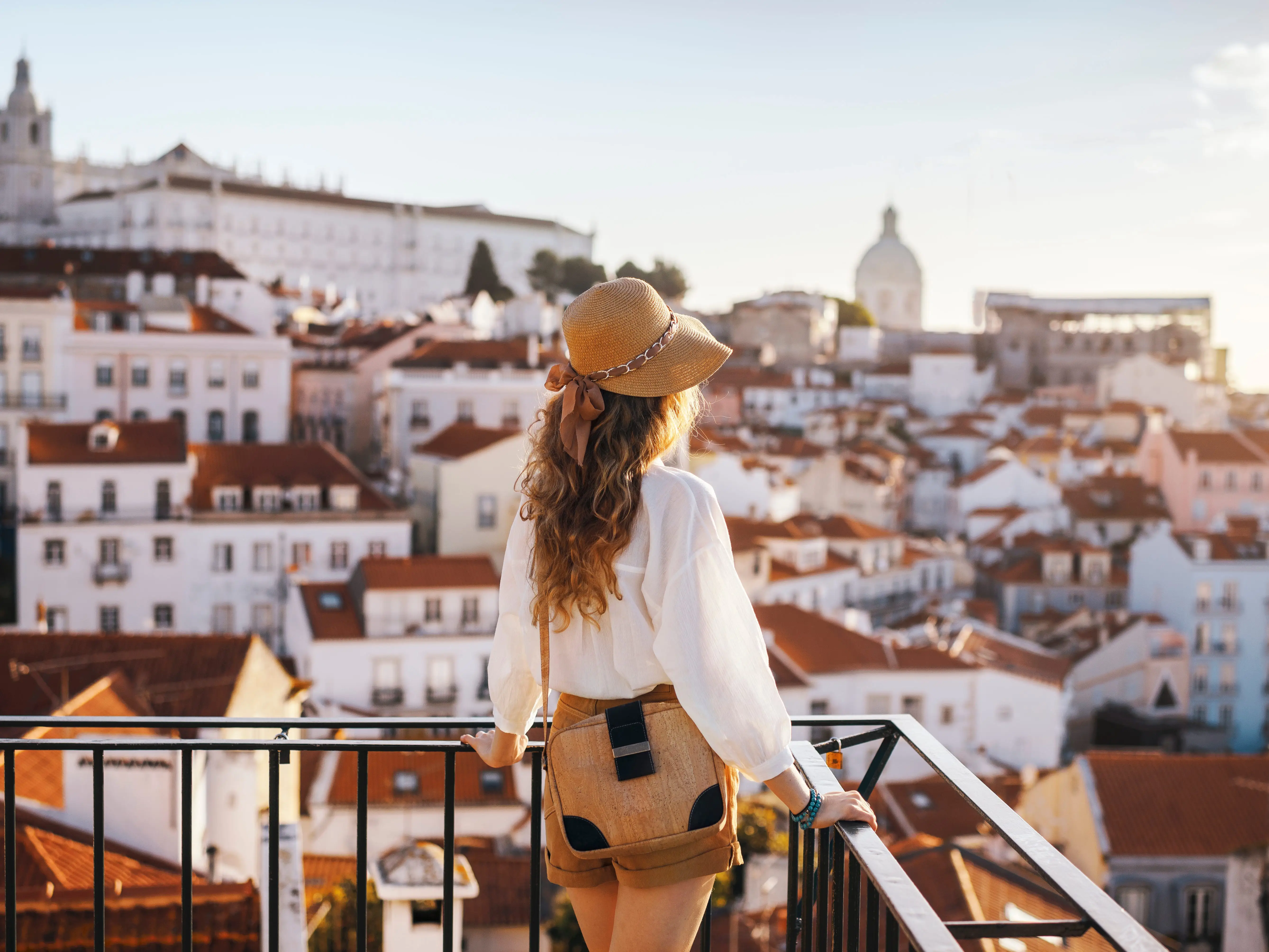 A woman stands on a balcony and looks out at a city.