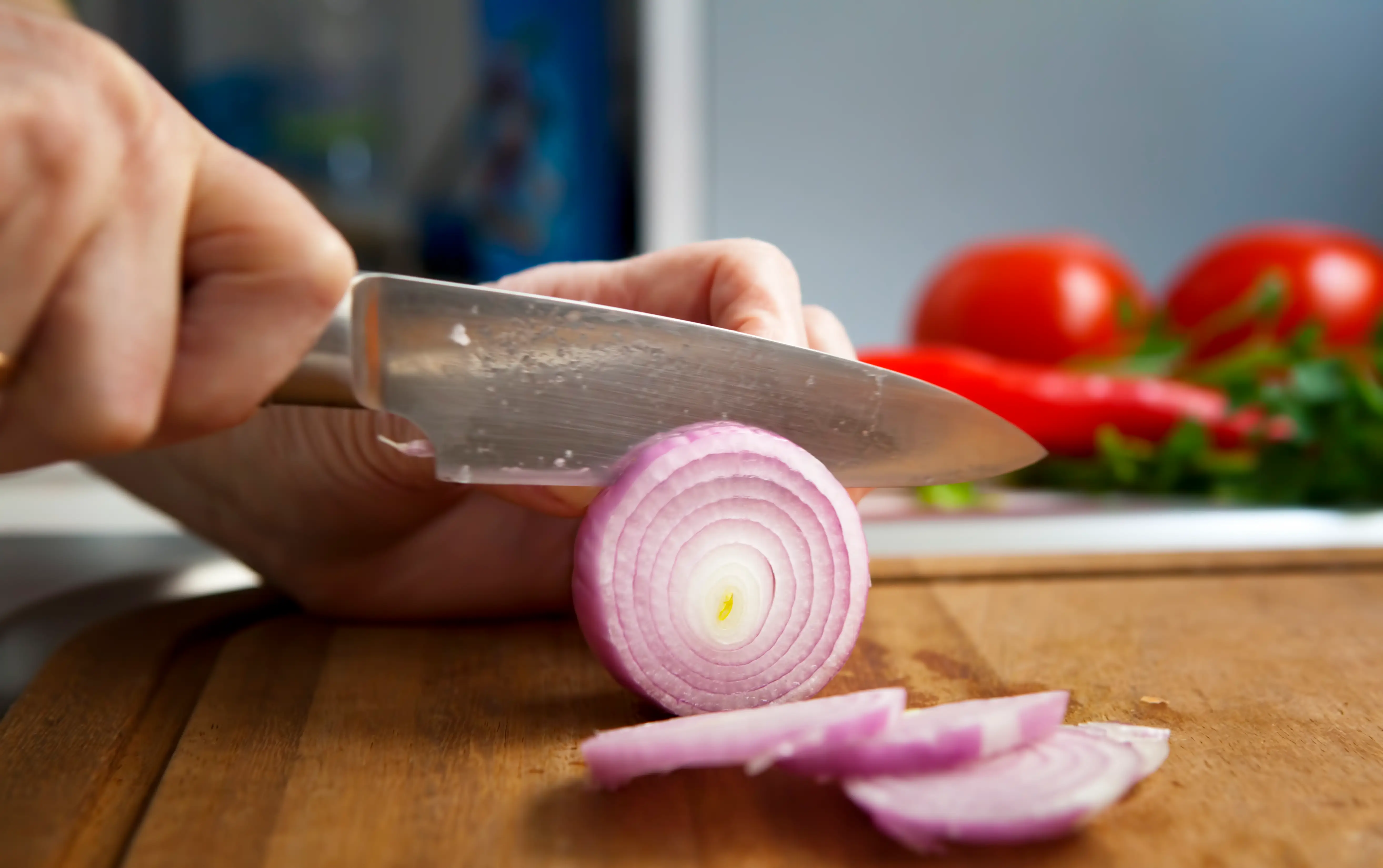 Knife slicing red onion