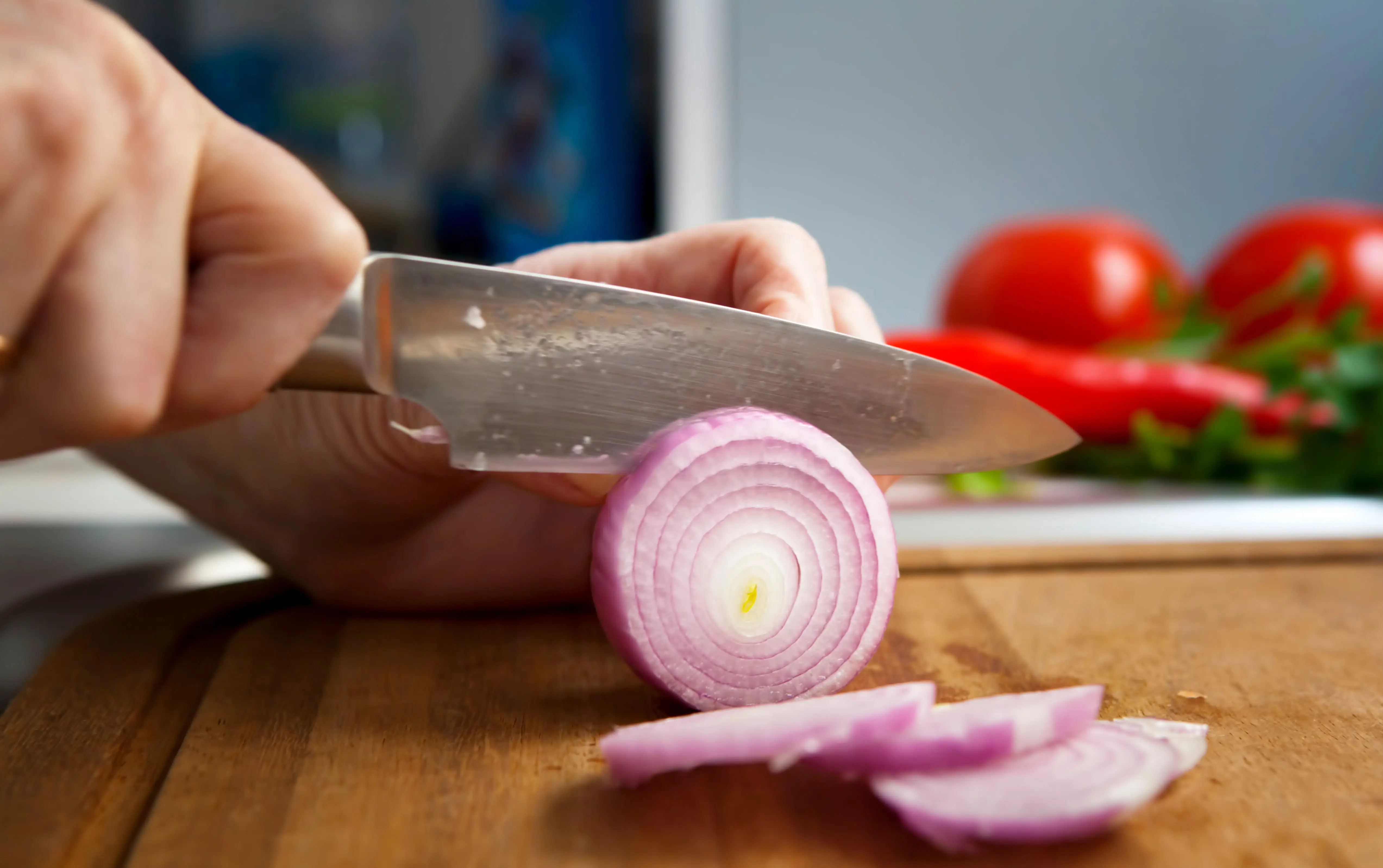 Knife slicing red onion