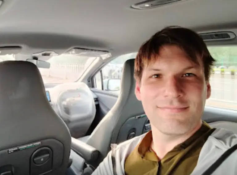 Man in Chinese robotaxi in Wuhan smiles at camera.