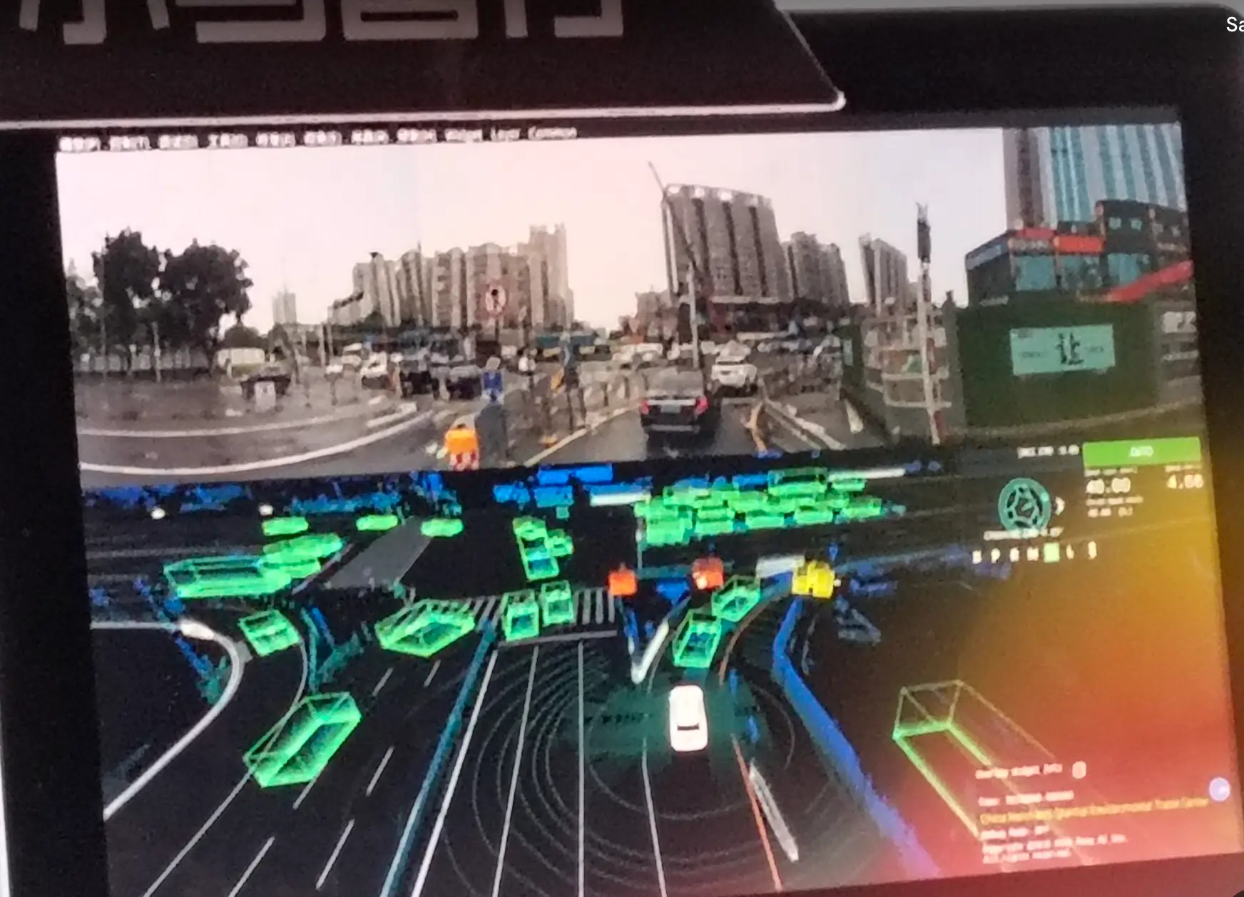 A screen in a Pony robotaxi in Shenzhen depicting other cars (green), pedestrians (yellow), and two-wheelers (orange) in the driving environment.