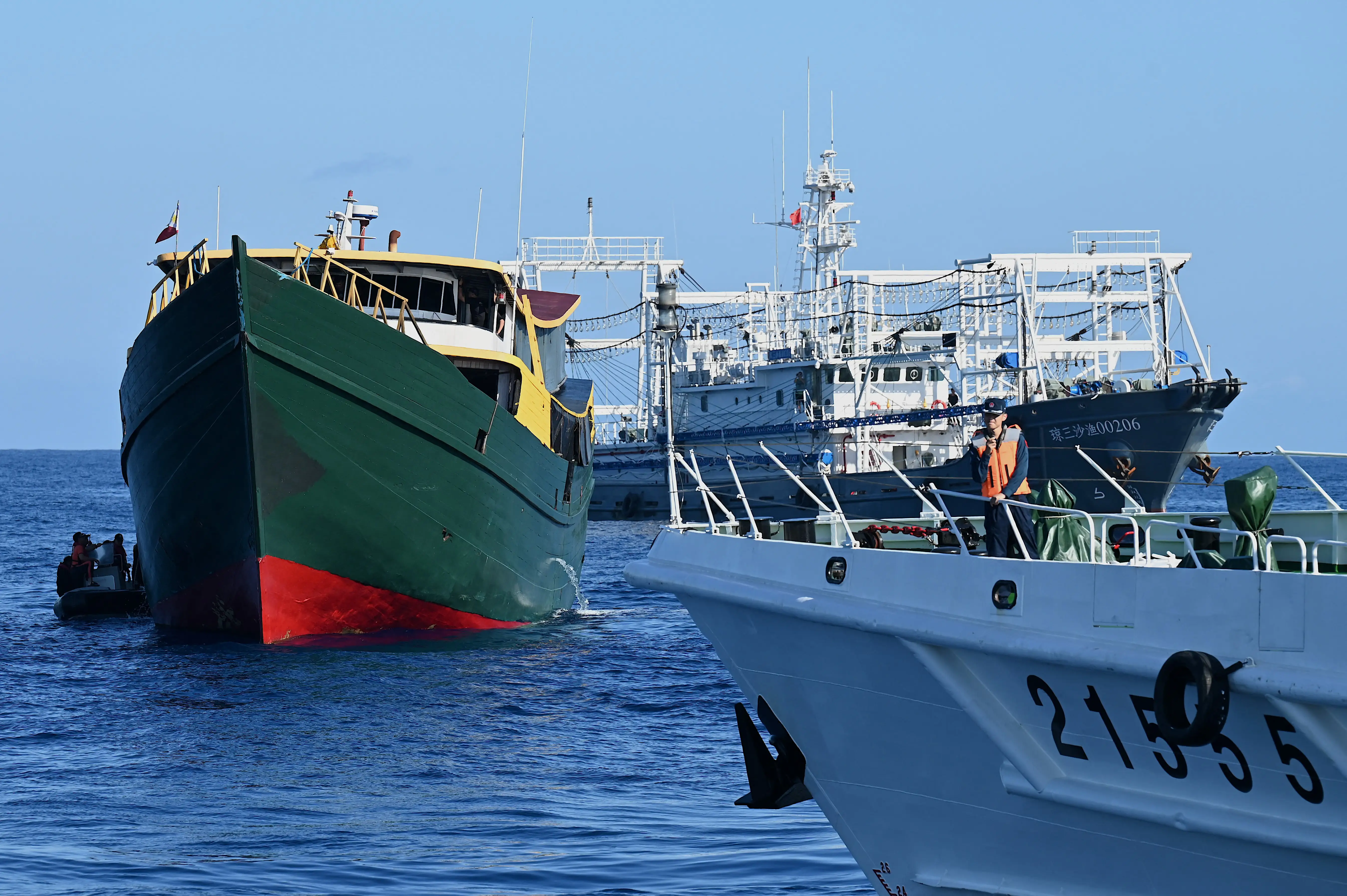 Three fishing boats sit in blue water with a clear sky in the background.