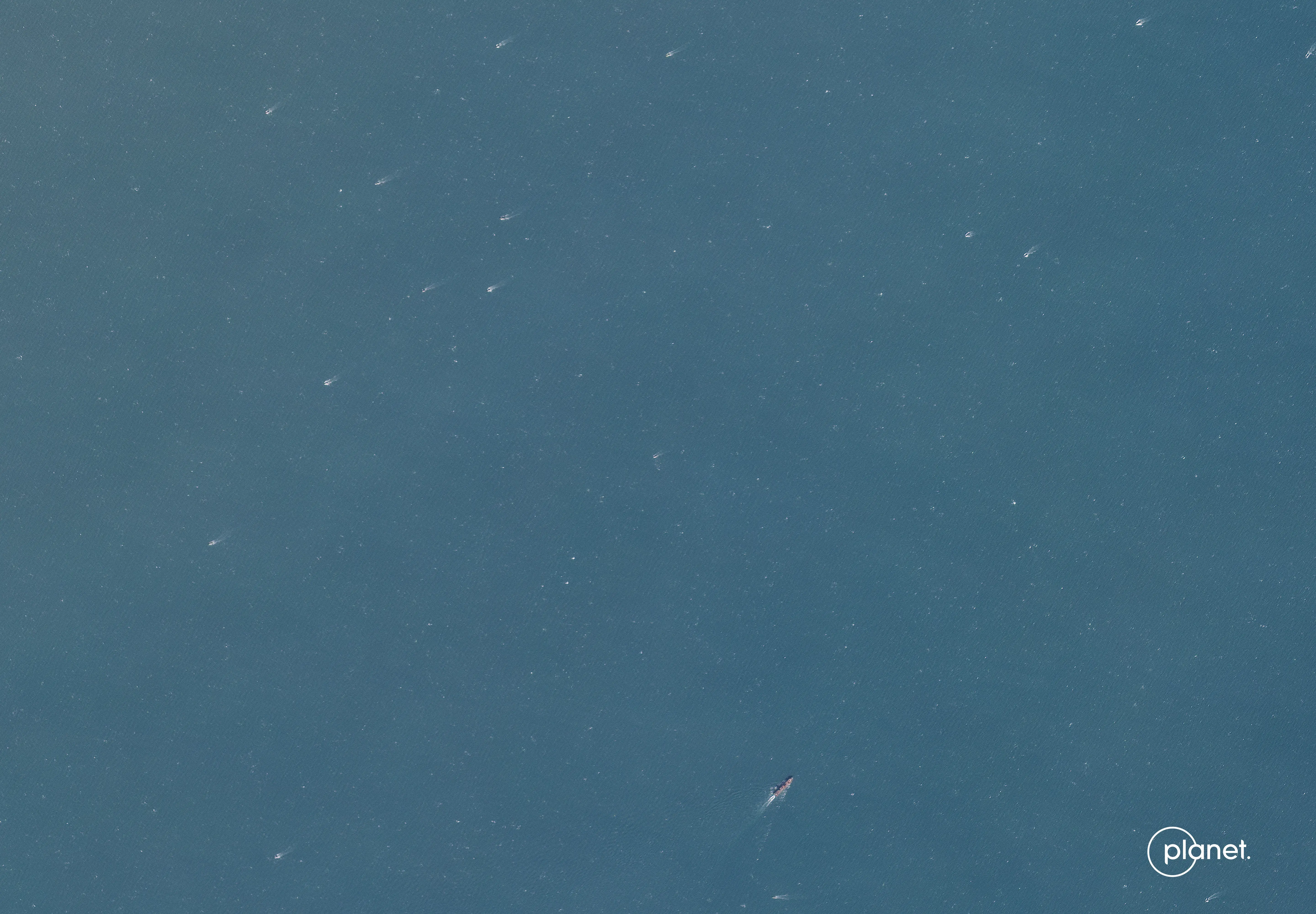 A satellite image showing ships sailing in the ocean.