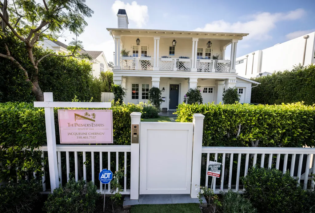 A white, two-story house with a balcony and an 