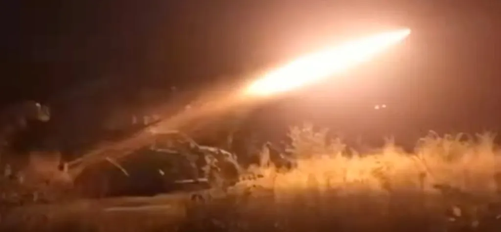 A bright missile launching from a vehicle in a field at night.
