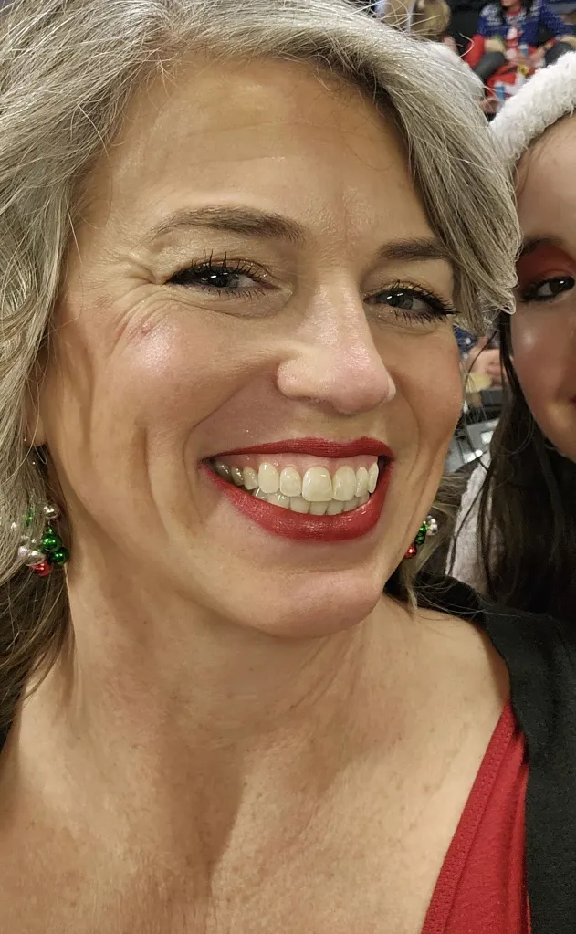 A close-up of Jerri Mains smiling and wearing festive earrings.