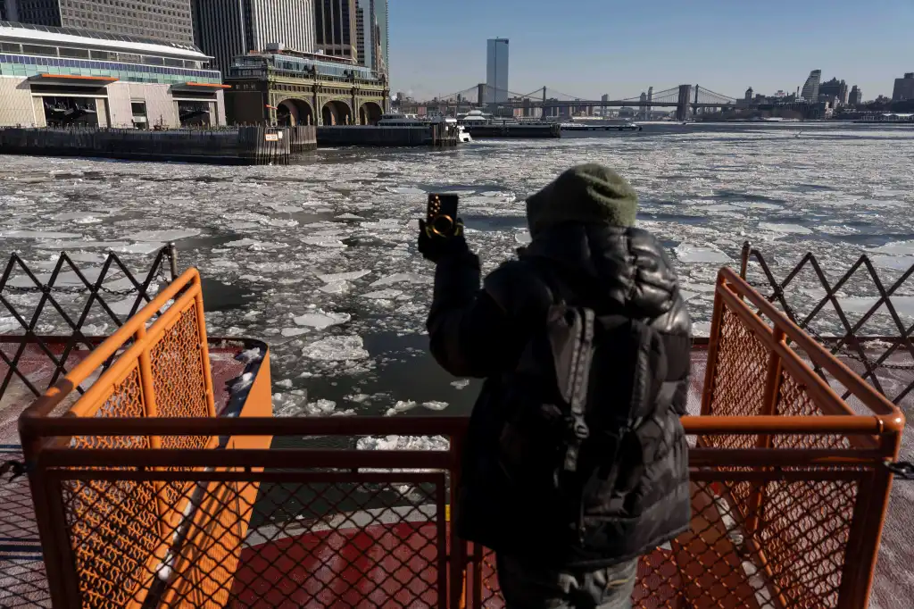 Person on a ferry taking a photo of a frozen New York City harbor and skyline.