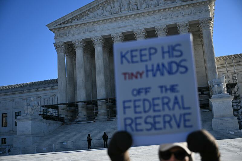 A protester holds a sign outside the U.S. Supreme Court in Washington, DC, on January 21, 2026 as the justices were set to hear oral arguments on the president's attempt to fire Federal Reserve Board Governor Lisa Cook.