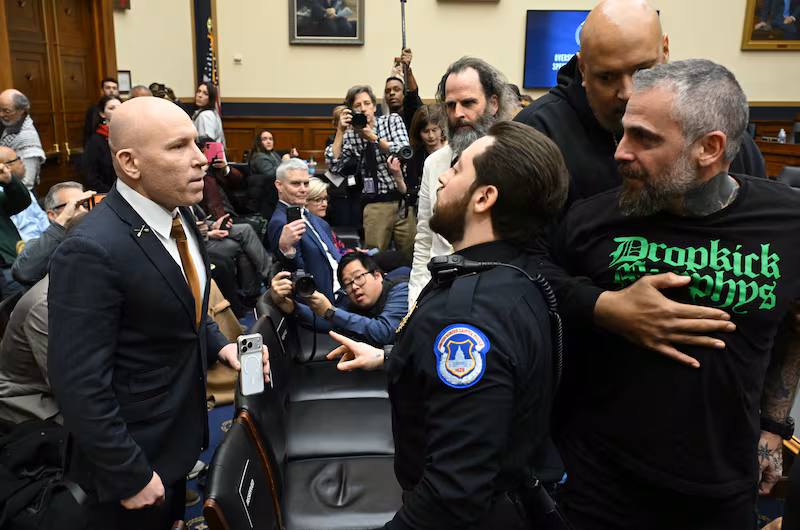 A U.S. Capitol Police officer intervenes as far-right political operative Ivan Raiklin (left) confronted former Metropolitan Police Department officer Michael Fanone (right) as he's held back by former U.S. Capitol Police Officer Harry Dunn during a break in testimony by former Special Counsel Jack Smith before the House Judiciary Committee on January 22, 2026.