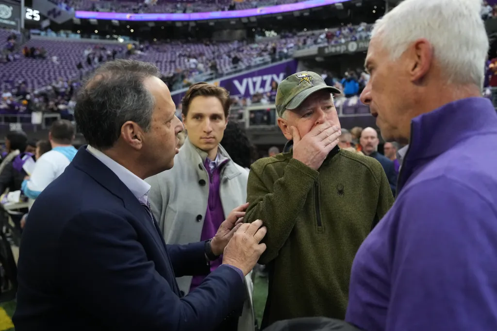 Mark Wilf, left, owner and president of the Minnesota Vikings, talks with with Minnesota Governor Tim Walz, in green hat, on the sidelines ahead of an NFL football game between the Minnesota Vikings and the Washington Commanders Sunday, Dec. 7, 2025