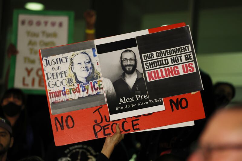 A sign is raised in support of Renee Good and Alex Pretti at a candle light vigil during a peaceful protest in support of a 37-year-old man shot and killed by immigration officers in Minneapolis was under way Saturday evening along Olvera Street in Los Angeles.