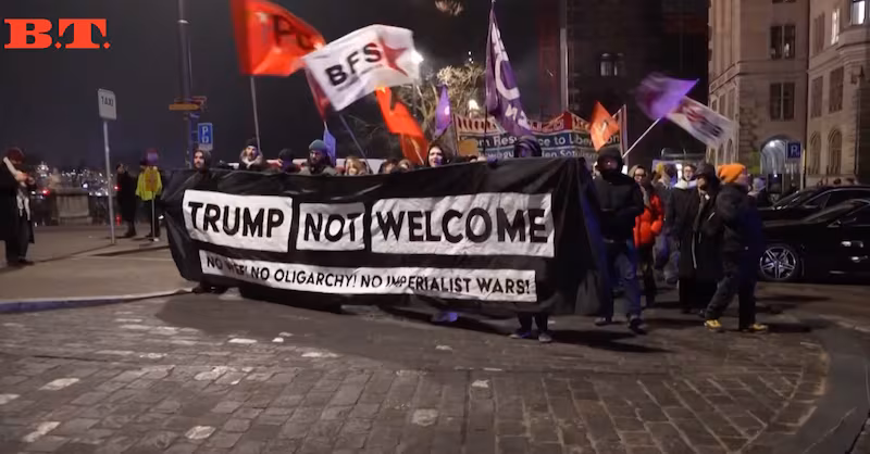 Protesters carry a 'Trump not welcome' banner.