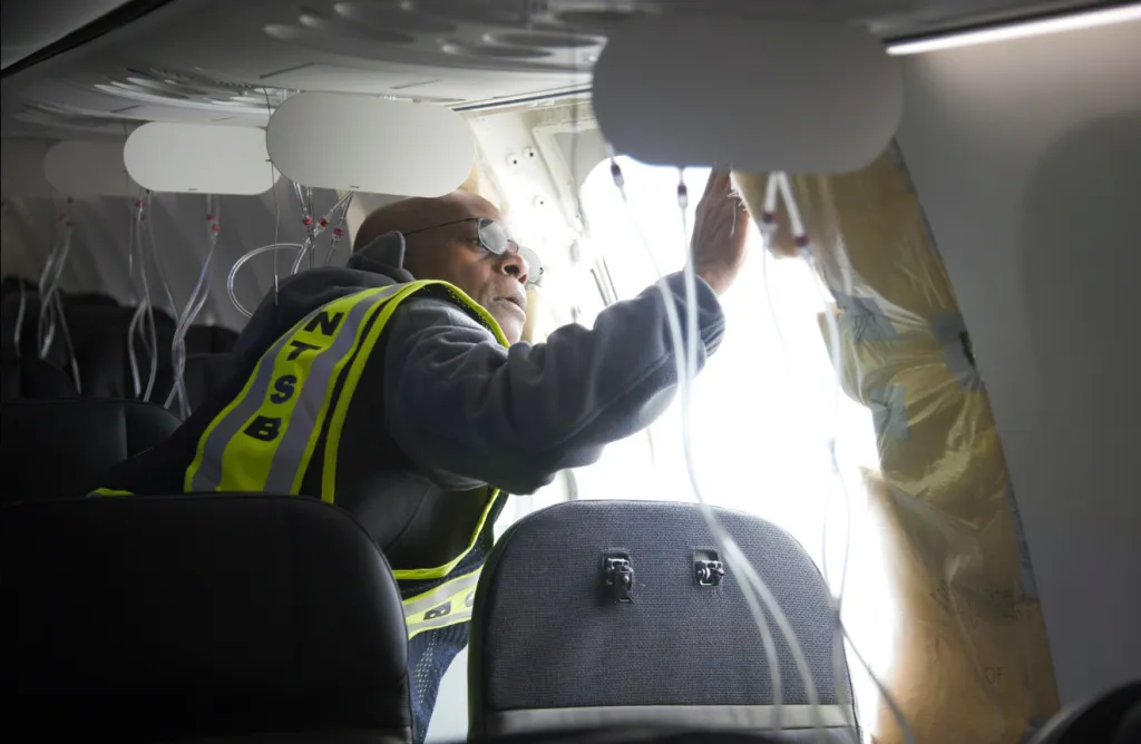 A National Transportation Safety Board investigator examines the fuselage plug area of Alaska Airlines Flight 1282.