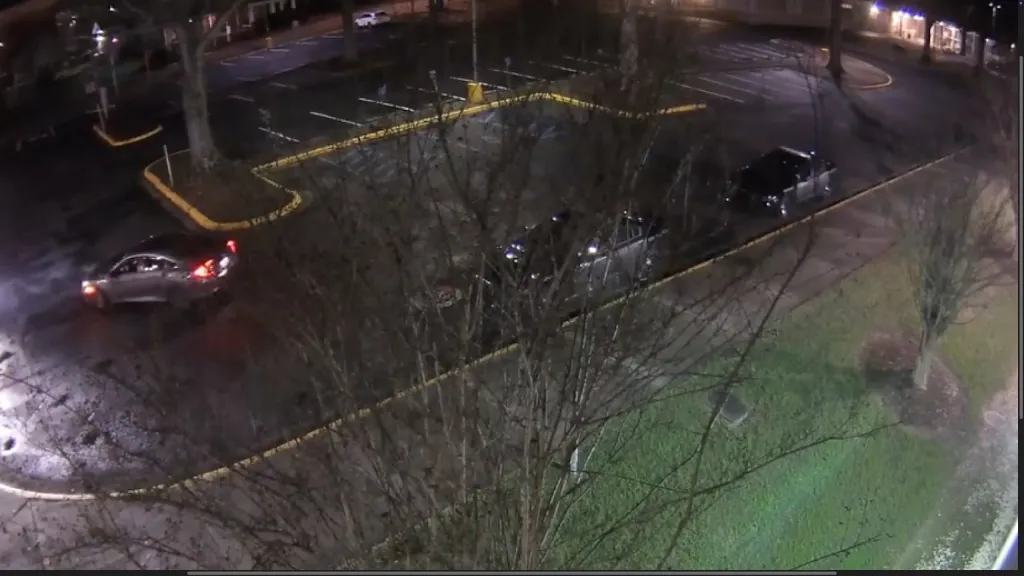 Surveillance video shows a vehicle traveling through a parking lot at night in Greenville. Police said the vehicle was involved in a shooting that targeted one officer.