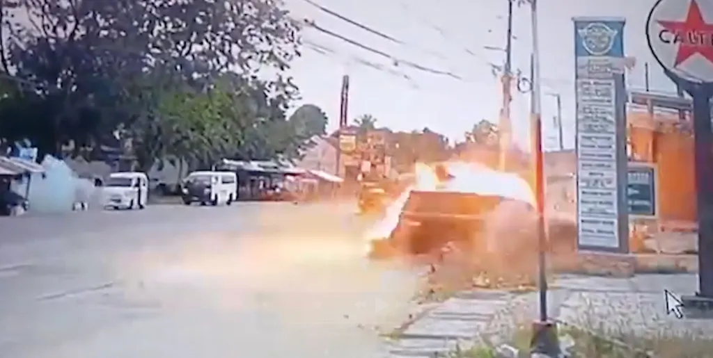 Explosion from a crash on the side of a street with vehicles passing by.