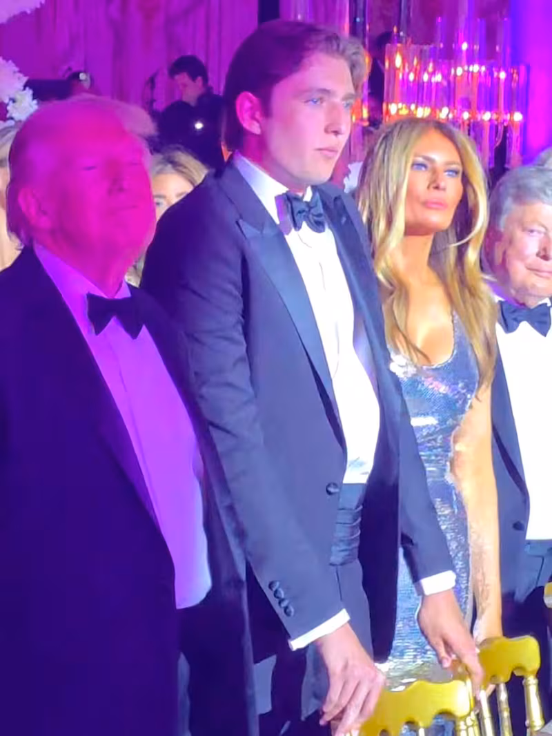 Barron Trump stands between his president after, Donald, and FLOTUS's mother, Melania, at the New Year's party at Mar-a-Lago.