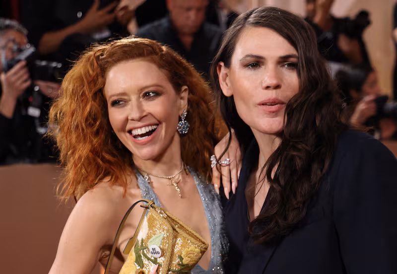 US actress Natasha Lyonne (L) holds up her purse with a pin reading "be Good", in tribute to Renee Good, who was fatally shot by a US Immigration and Customs Enforcement (ICE) agent in Minneapolis, as she and US actress Clea DuVall attend the 83rd annual Golden Globe Awards at the Beverly Hilton hotel in Beverly Hills, California, on January 11, 2026.