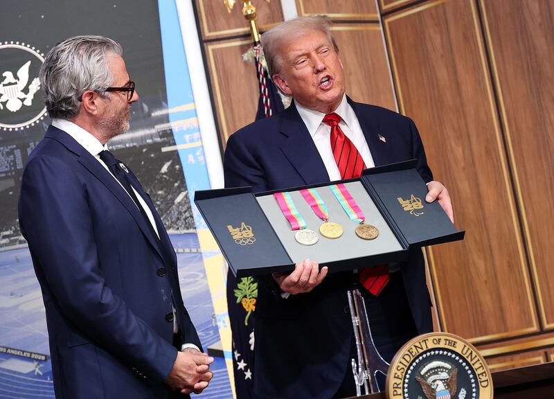 U.S. President Donald Trump displays a set of 1984 Los Angeles Olympic medals given to him by Chairman of the 2028 LA Olympics organizing committee Casey Wasserman (L) during an executive order signing ceremony in the South Court Auditorium in the Eisenhower Executive Office Building on August 5, 2025 in Washington, DC.