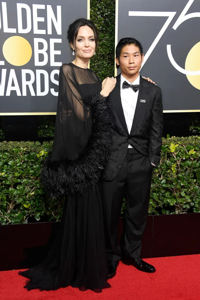 Angelina Jolie in a black gown and Pax Thien Jolie-Pitt in a tuxedo at the 75th Annual Golden Globe Awards.