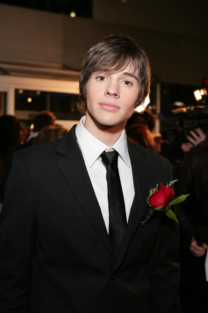 Actor Matt Prokop in a pinstripe suit with a red rose boutonnière.