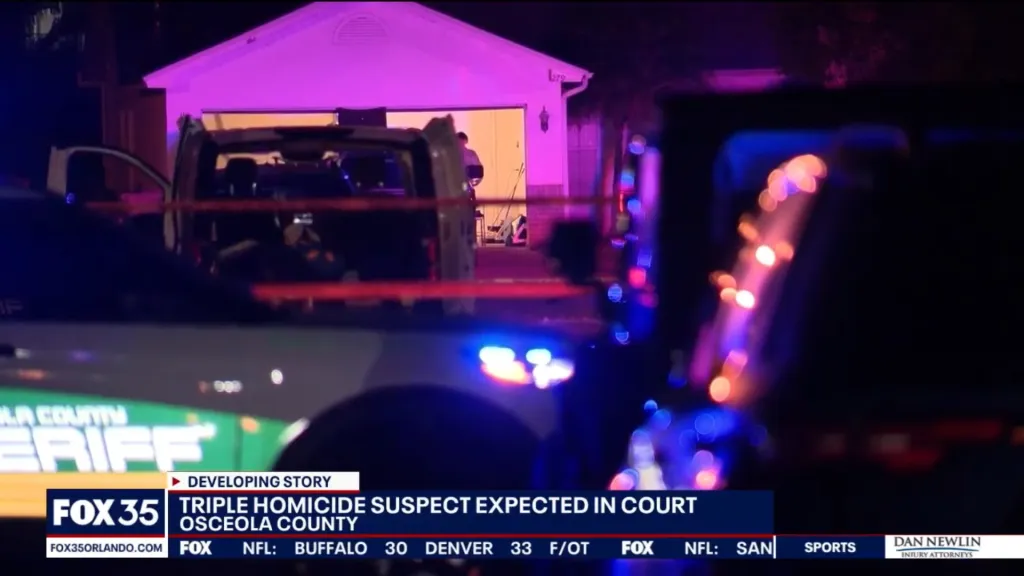 Law enforcement vehicles with flashing lights outside a house at night, with an onscreen caption about a triple homicide suspect.