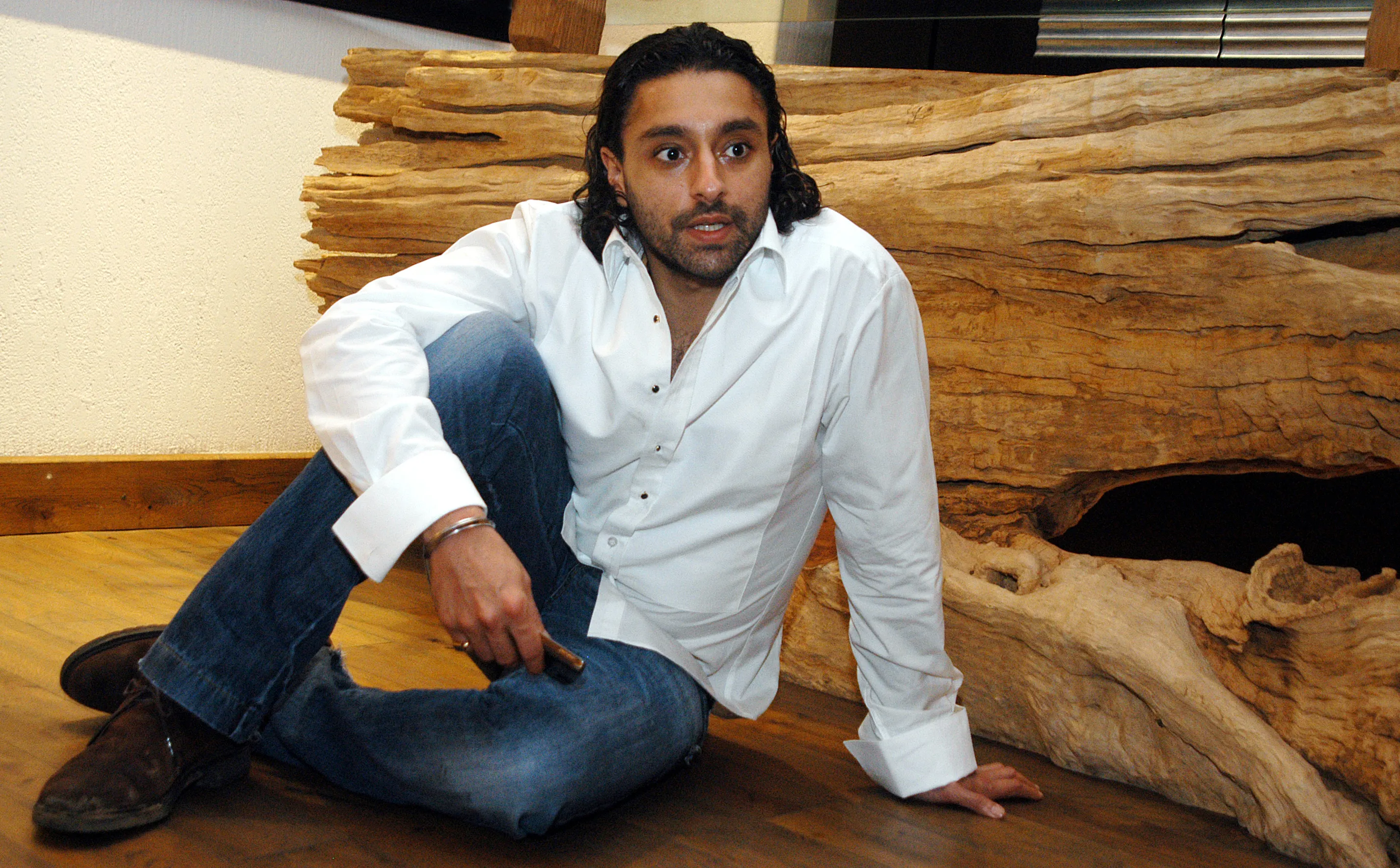 Vikram Chatwal, American hotelier and actor, sitting on the floor in a white shirt and jeans.