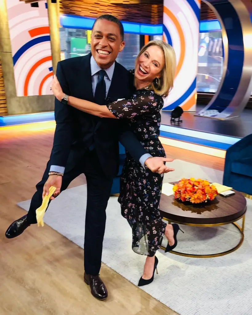 Amy Robach and T.J. Holmes smiling and embracing each other on a television set.