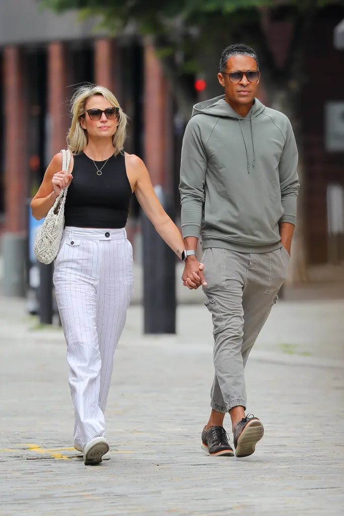 Amy Robach and TJ Holmes walking together, holding hands.