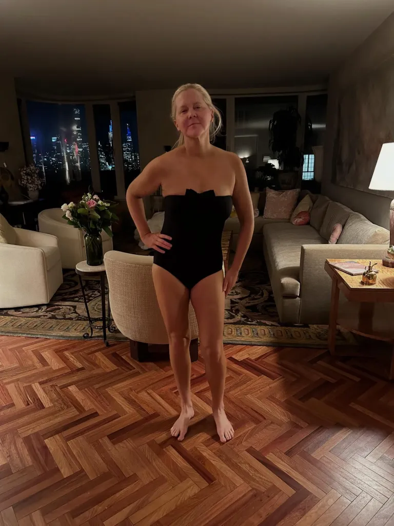 Amy Schumer posing in a black strapless swimsuit.