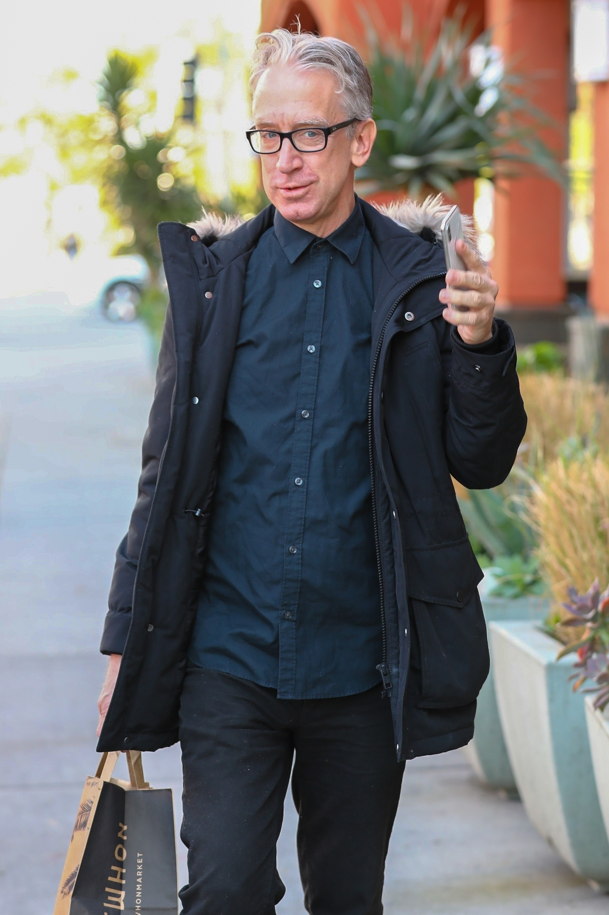 Actor and comedian Andy Dick holding a phone and a shopping bag from Erewhon Market.