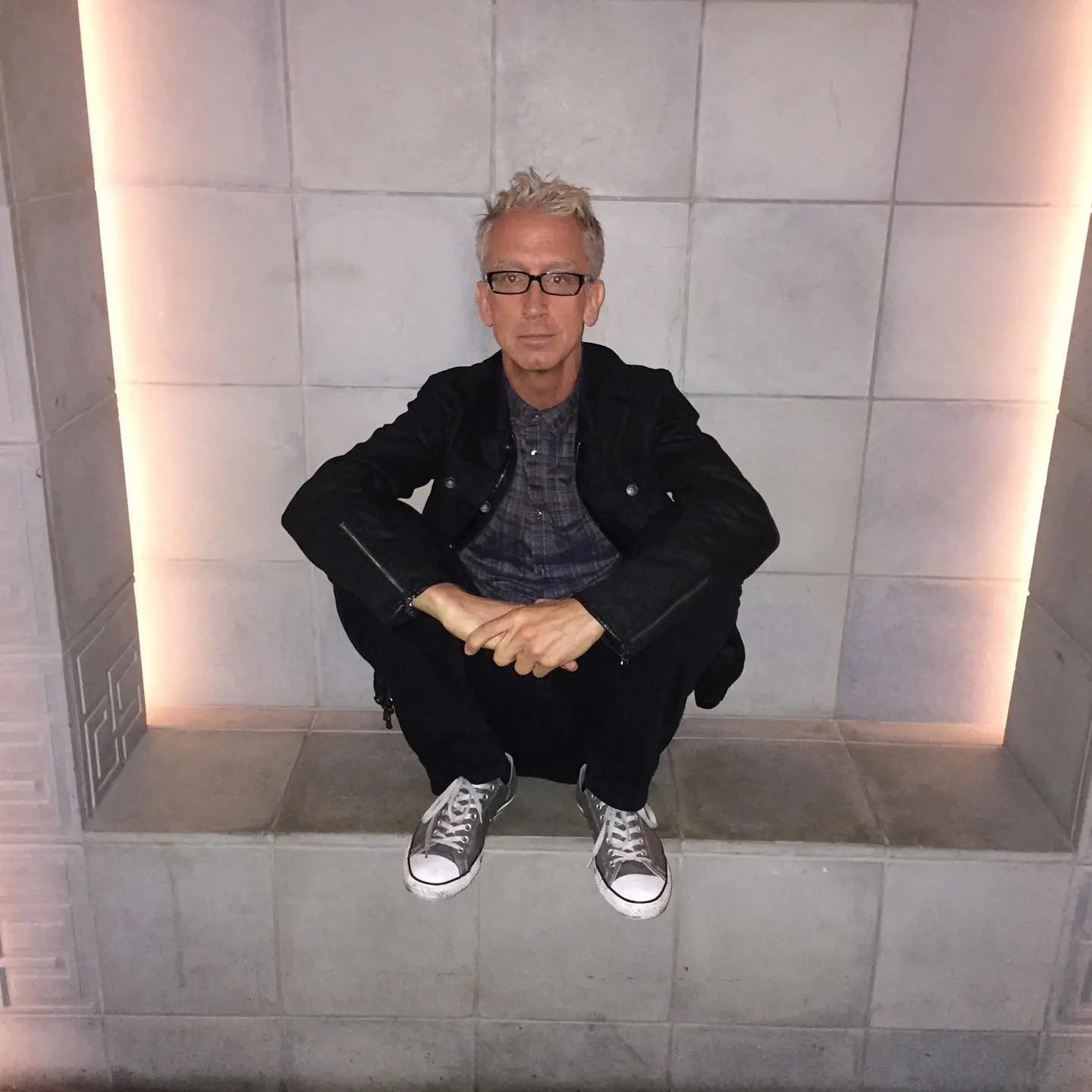 Andy Dick sitting on a ledge.