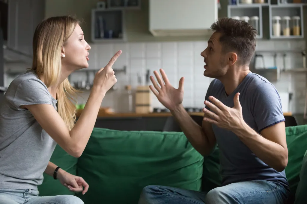 Angry man and woman sitting on a couch and arguing.