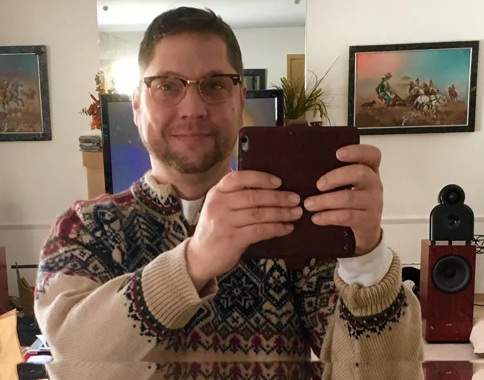 Anthony James Kazmierczak looking at the camera while holding a tablet.