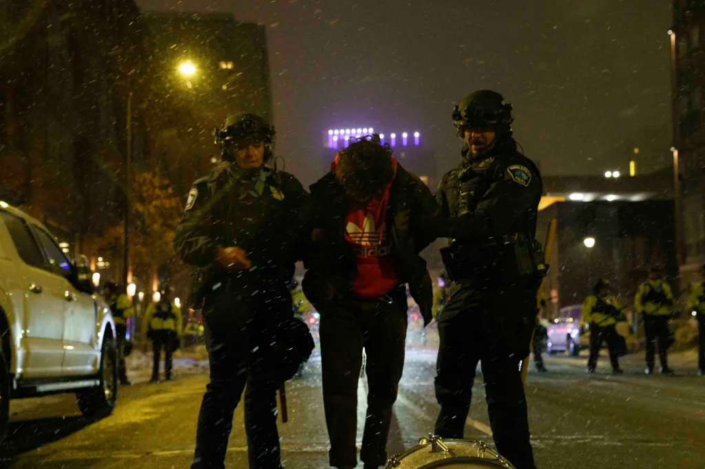 Two police officers arresting a protester during an anti-ICE demonstration in Minneapolis.