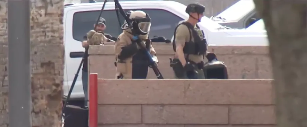 A bomb squad technician in a protective suit and two police officers stand near the Arizona Supreme Court building.
