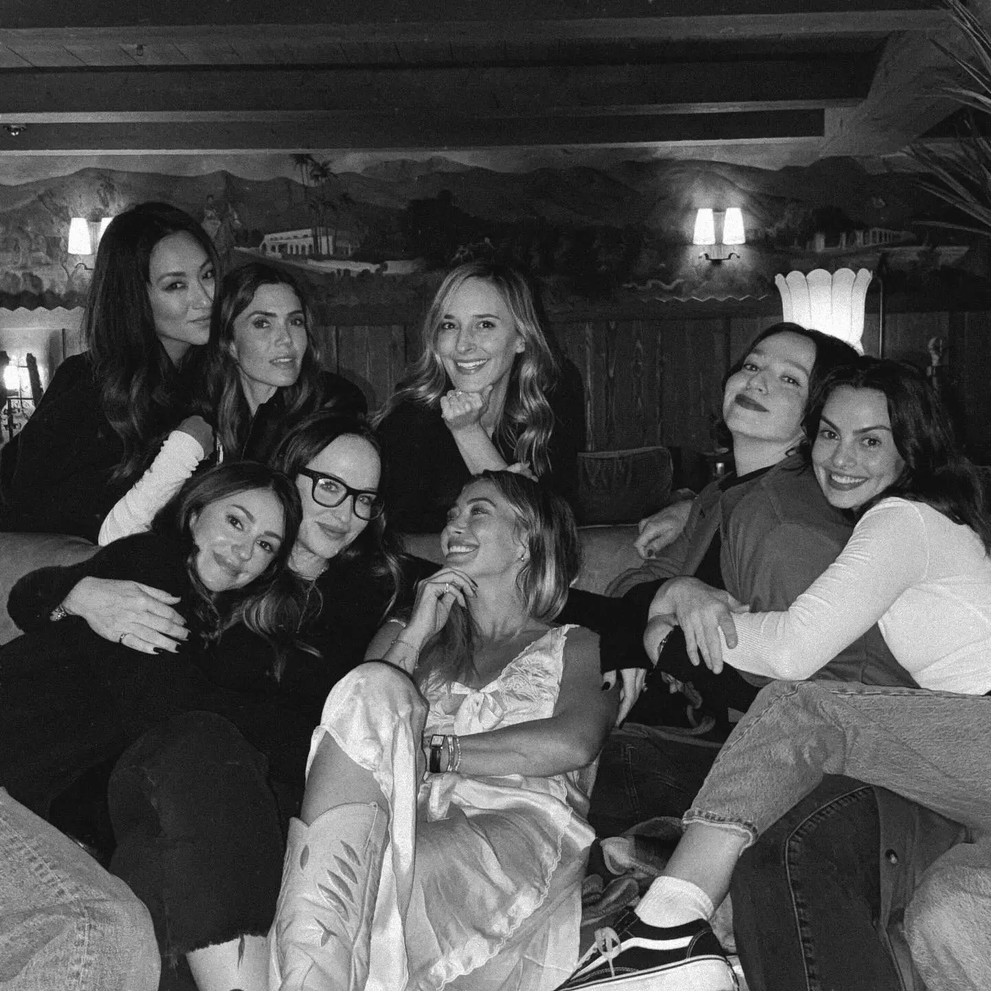 Black and white photo of eight women posing for a group picture on a couch.