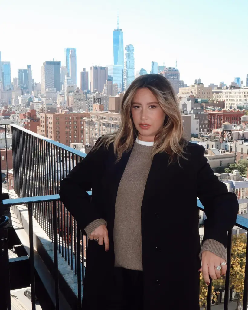 Ashley Tisdale on a balcony overlooking the New York City skyline.