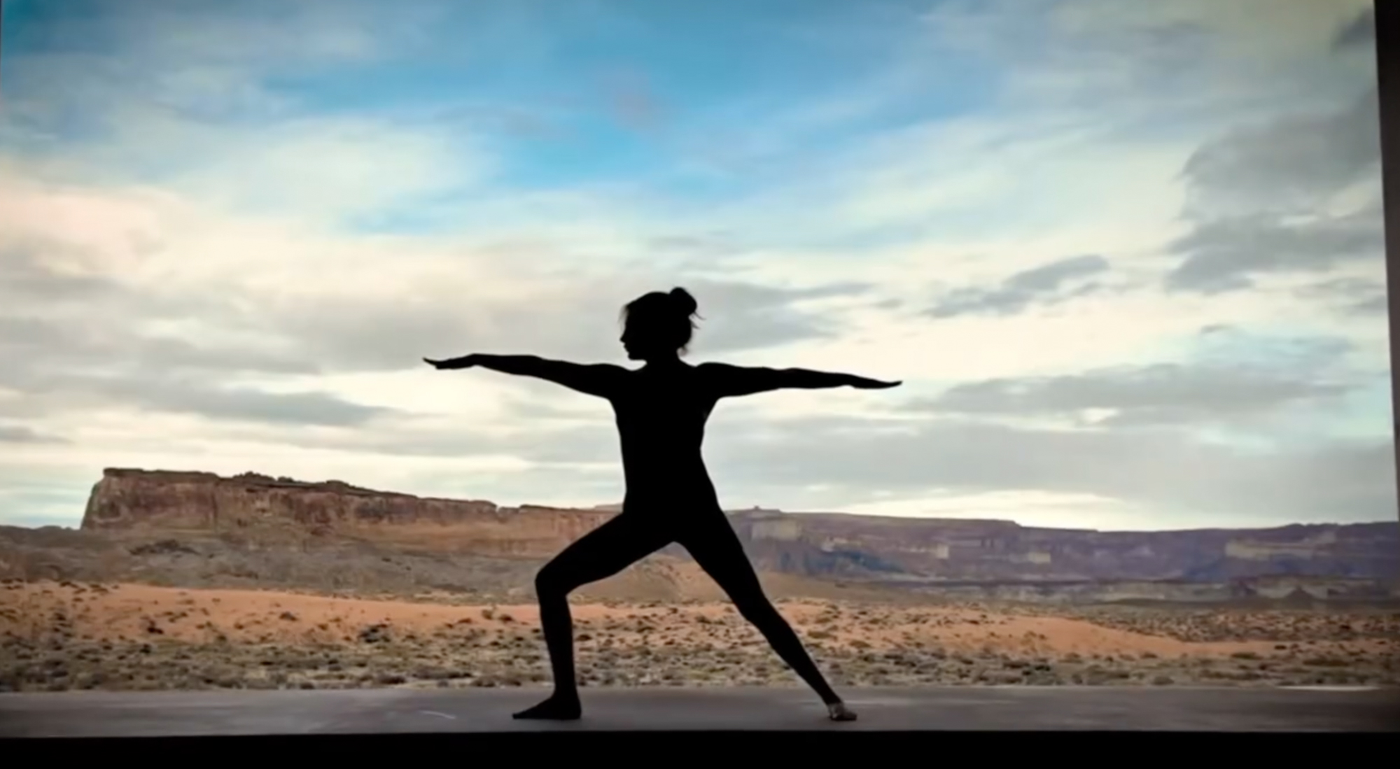 Silhouette of a woman doing yoga in a desert landscape.