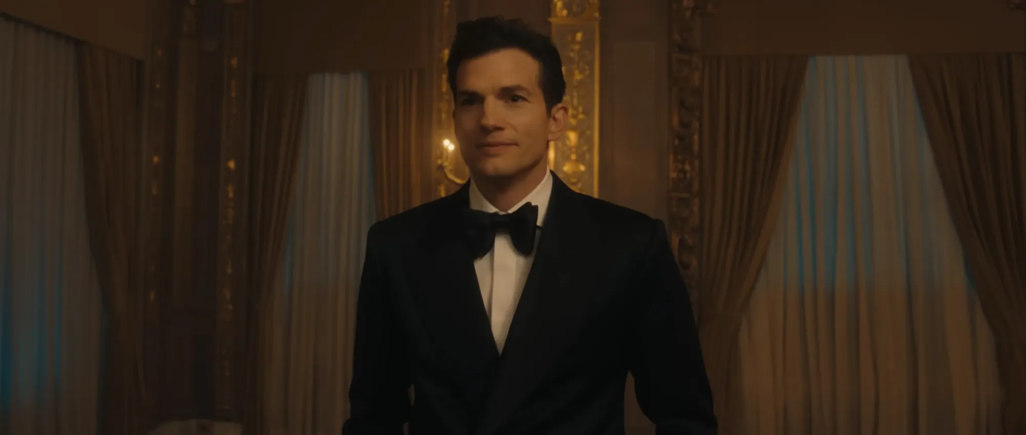 Ashton Kutcher in a black suit and bow tie.