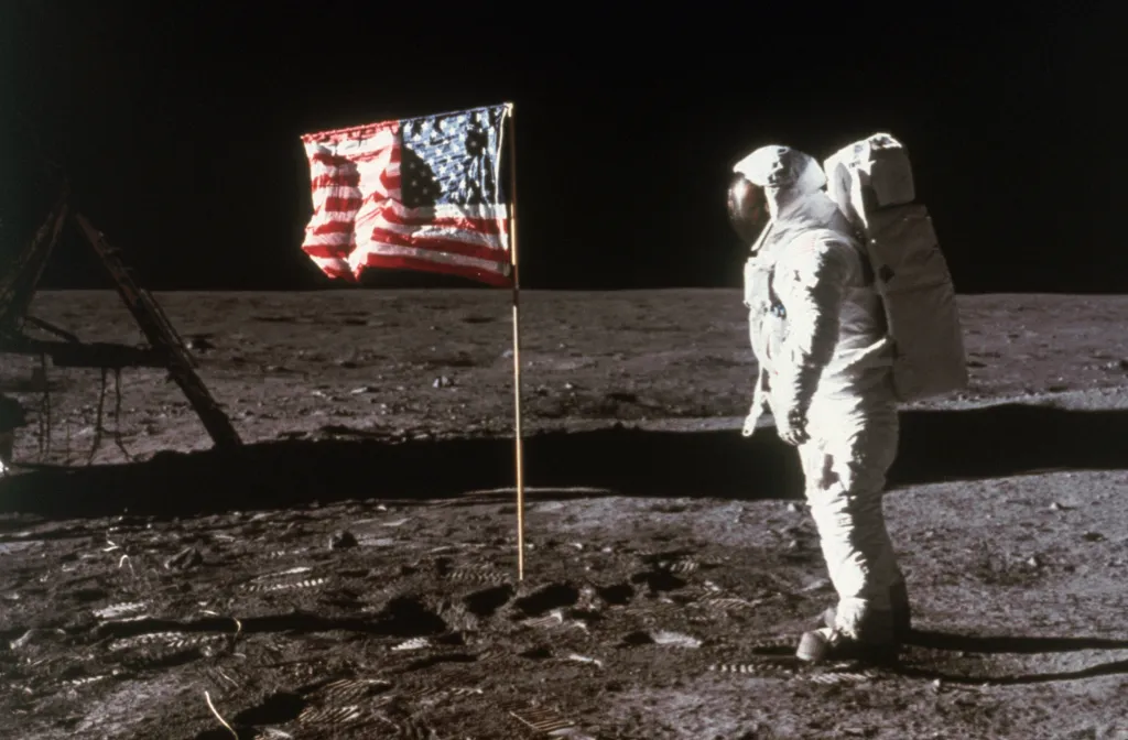Astronaut Buzz Aldrin stands by an American flag planted on the Moon.