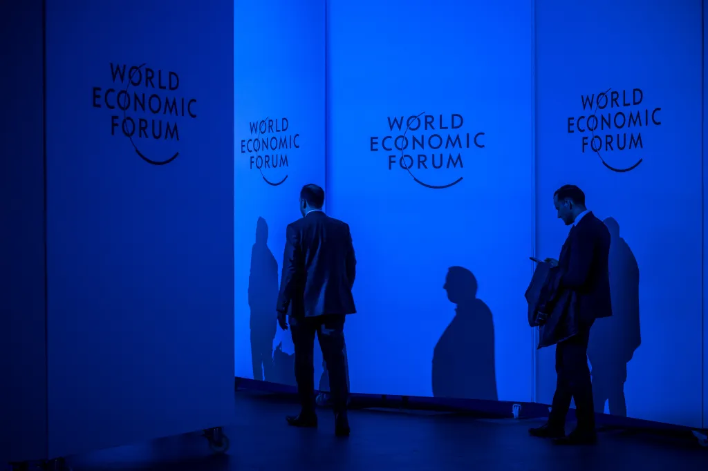 darkened figures against world economic forum backdrop
