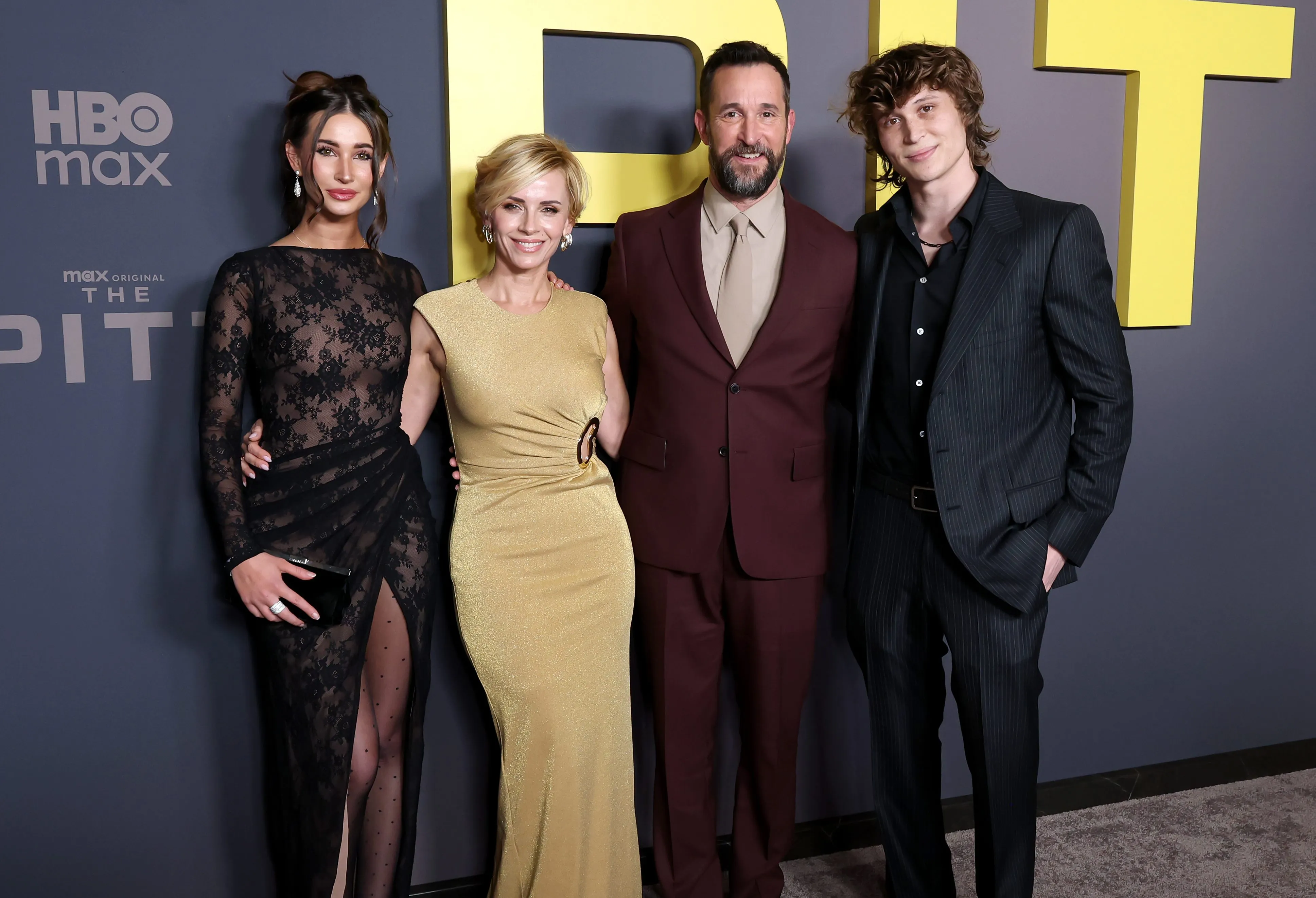 From left to right: Auden Wyle, in a sheer black gown, Sara Wells,in a mustard gown, Noah Wyle, in a burgundy suit and grey shirt and tie, and Owen Strausser Wyle, in a black suit and shirt, posing on the red carpet.