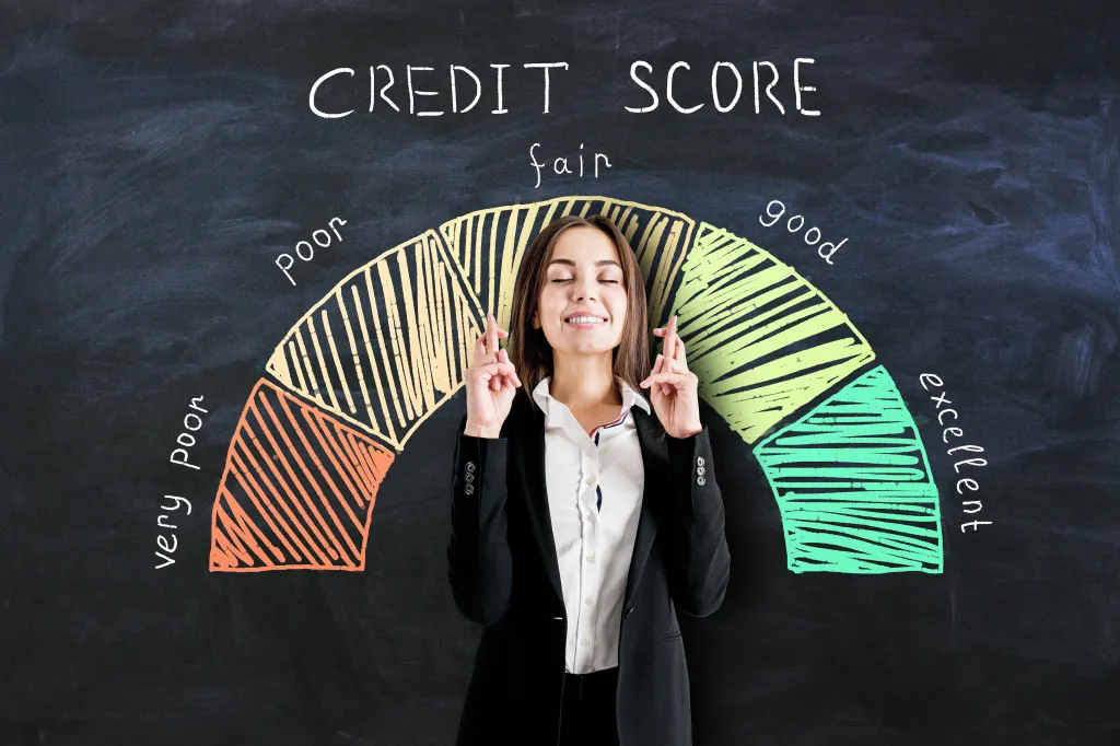 A businesswoman crossing her fingers, standing in front of a credit score scale drawn on a blackboard.