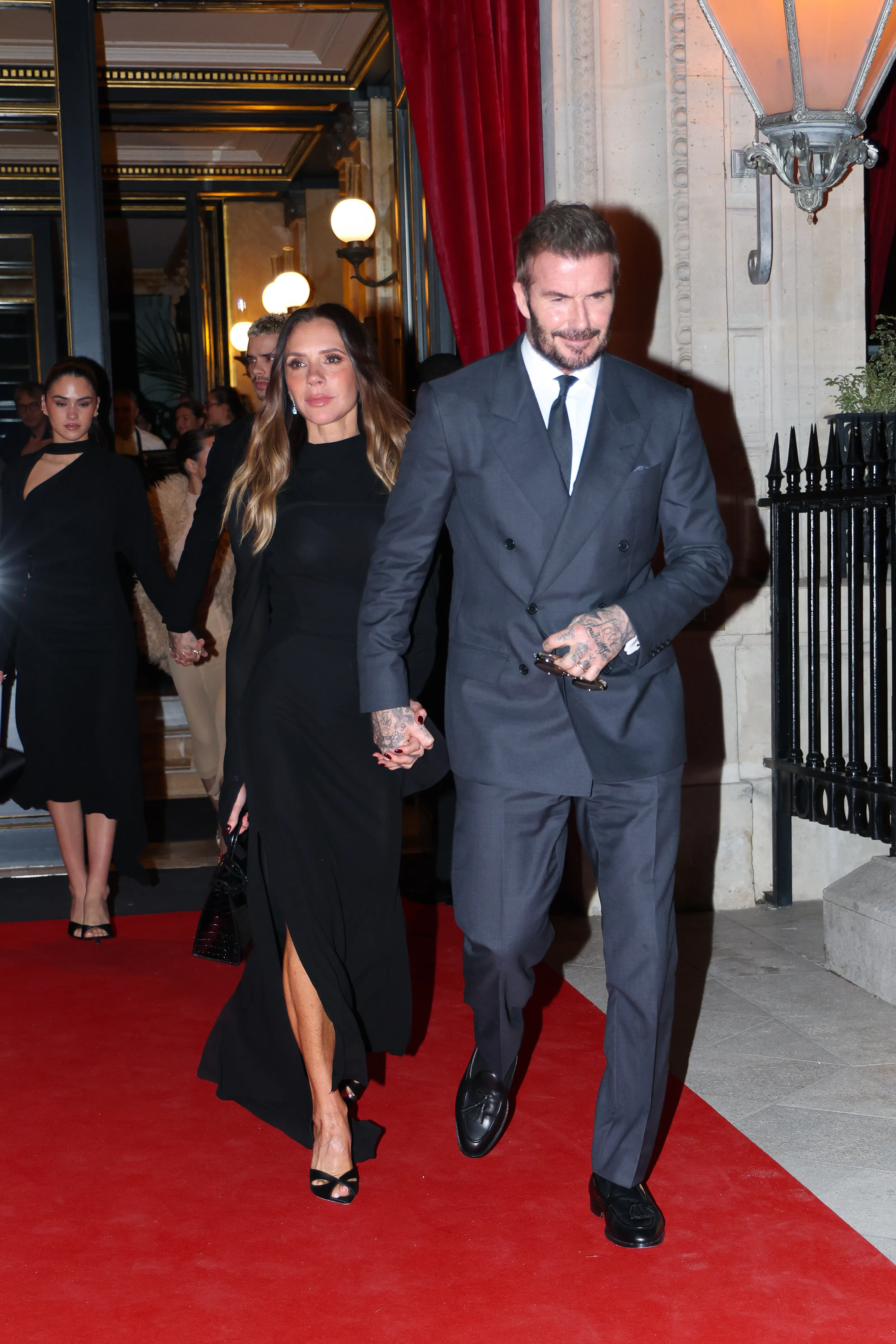 Victoria and David Beckham holding hands on a red carpet.