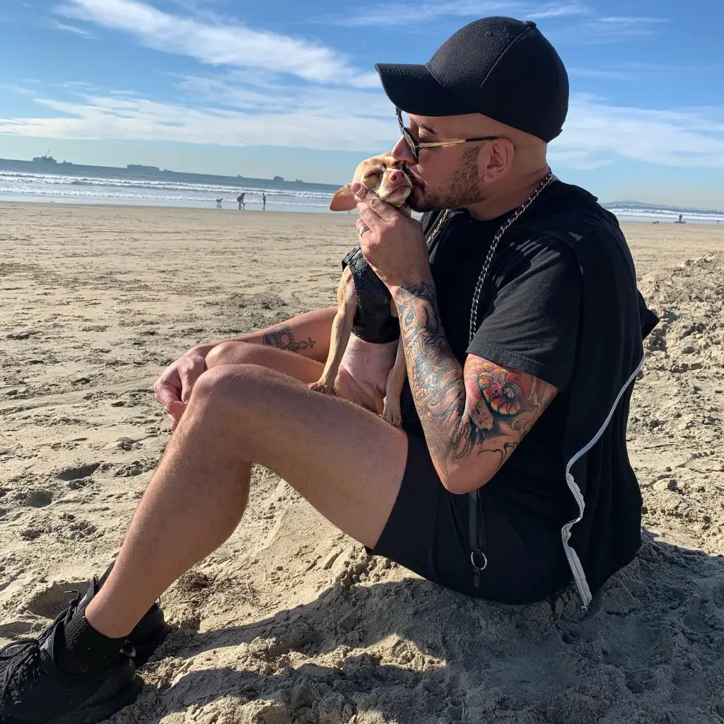 Jasen Kaplan kissing a small dog on a beach.