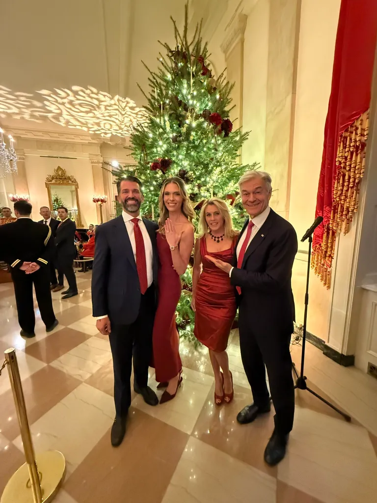 Bettina Anderson, Donald Trump Jr., and two other people pose in front of a Christmas tree.